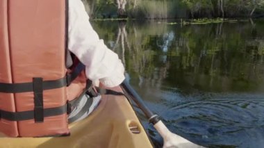 Kapalı kapılar ardında genç yetişkin bir kadın yaz günü bir gölde kano sürüyor kırsal alanda, macera yolculuğu keyfi konsepti, yaşam tarzı sporu tatili