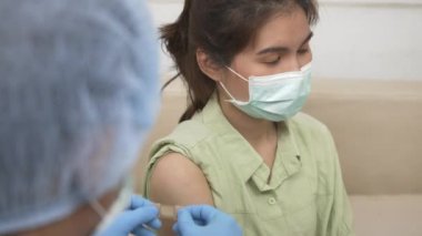 Aşı, Doktor Bey genç bir kadının omzuna koronavirüs aşısı yaptıktan sonra lastik koruyucu eldivenler yapıştırıcı bandaj sıva, Covid-19 İlaç ve Sağlık Konsepti koyuyor.