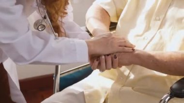 Kadın hemşire, tekerlekli sandalyede oturan yaşlı ve yaşlı bir adamın elini tutarak beyaz üniforma giyer. Hemşire hastanesinde cesaret ve empati, yaşlı insanların sağlık destek konsepti.
