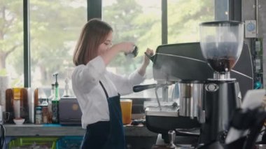 Kafenin kasasında çalışan önlüklü genç bayan barista, küçük işletme konsepti sahibi.