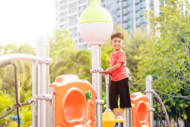 Asyalı çocuk dışarıda oyun oynuyor, anaokulunda mutlu küçük çocuk gündüz vakti oyun parkında oynarken eğleniyor, okul dışında eğitim görüyor, küçük çocuk tırmanıyor.