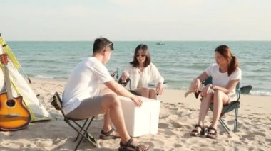 Kampta içkili mutlu arkadaşlar ve yaz tatillerinde birlikte kumsalda gülüşmeler gün batımında kamp kurma zamanı, genç Asyalı grup kadın ve erkek açık havada seyahat ediyorlar.