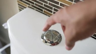 Elle ütüle ve tuvaletin suyunu temizle, erkek parmağı parlak metal boşaltma düğmesine basıyor, kişisel hijyen kavramı.