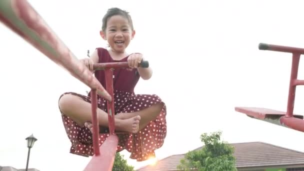 快乐的微笑可爱的小女孩在户外操场上玩耍玩乐吧 自由的孩子在夏天的日落下玩脚镣或荡秋千 — 图库视频影像