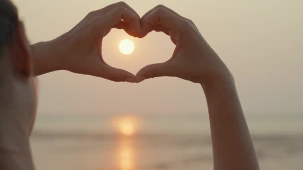 在热带夕阳西下的海滩上 轮廓手握心形 夏天快乐的爱情旅行和自由 女性的手紧握着天空 传递着阳光 情人节的概念 — 图库视频影像
