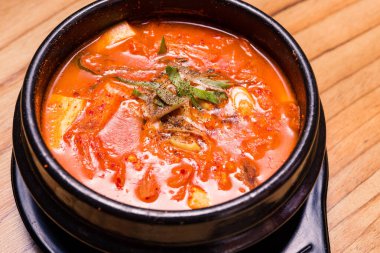 Kimchi çorbası sıcak, siyah tencerede, Kore geleneksel kimchi jjigae çorbası restoranda, Japon sıcak yemeği.