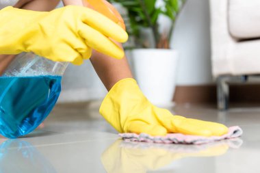 Sarılı lastik eldiven giyen Asyalı bir kadın. Evde bez parçası ve deterjan spreyi temizliyor. Kadın elleri temizlik işçisi, ev işi ve temizlik konseptini yıkıyor.