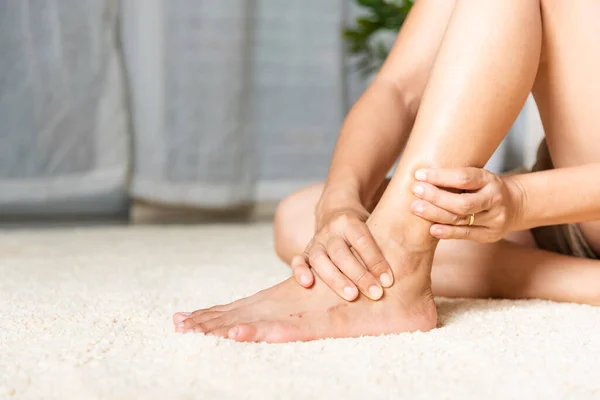 女人在家里抱著脚踝受伤的感觉脚痛 女人在家里用手压脚痛 家里用脚踝放松肌肉 保健问题和医疗 — 图库照片