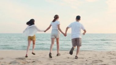 Mutlu arkadaşlar el ele tutuşup hayatın tadını çıkarıyorlar kumsalda birlikte özgürlüğün tadını çıkarıyorlar gün batımında tatil tatilinde genç Asyalı kadın ve erkek yaz seyahatinde, insanların yaşam tarzı