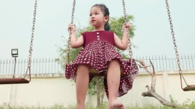 Mutlu gülümseyen küçük kız dışarıda oyun oynarken salıncakta sallanırken eğlen, özgürlük çocuğu yazın günbatımında zincir sallarken.