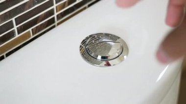 Elle ütüle ve tuvaletin suyunu temizle, erkek parmağı parlak metal boşaltma düğmesine basıyor, kişisel hijyen kavramı.