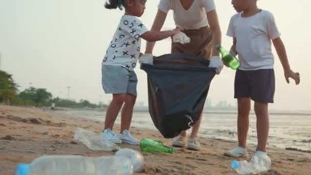 ボランティアの幸せな家族は ビーチ 母と彼の子供たちが日没 生態系と世界環境の日にゴミをきれいにするために黒のゴミプラスチック製の袋にペットボトルを選ぶ 地球の概念を保存 — ストック動画