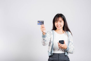 Gülümseyen bir kadın cep telefonu ve kredi kartı ile ödeme stüdyosu için kredi kartı, izole edilmiş beyaz arka plan, akıllı telefon alan ve online alışveriş yapan mutlu genç kadın.