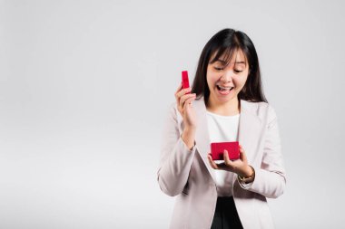 Gülümseyen kadın özgüveni, avuç içi izole edilmiş beyaz arka planda kırmızı bir hediye kutusu açıyor, sürpriz doğum günü veya Noel günü ve sevgililer günü, Asyalı mutlu portre güzel genç bayan stüdyo resmi, kopyalama alanı