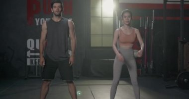 İki kaslı genç beyaz adam ve Asyalı kadın gülme egzersizi yapıyorlar vücut geliştiriciler spor salonunda antrenman yapıyorlar sağlık kulübünde sağlıklı çiftler için spor yapıyorlar.
