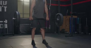 Genç kaslı beyaz adam ağırlık kaldırarak egzersiz yapıyor ağır halterler kaldırıyor erkek vücut geliştirici beden eğitimi ve spor salonunda tek başına antrenman yapıyor.