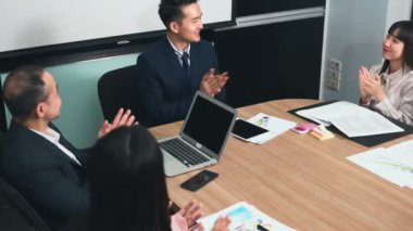 İş adamları birlikte çalışacaklarına ve iletişim kuracaklarına ve alkışlayacaklarına güveniyorlardı. Başarılarını alkışlıyorlardı. Ofisteki toplantı odasında mutlu ve gülümsüyorlardı.