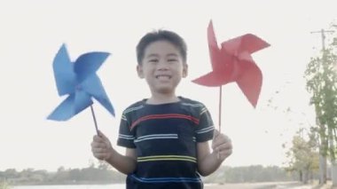 Mutluluk küçük çocuk buğday tarlasında gülümsüyor küçük rüzgar çarkı ya da yel değirmeni oyuncağı tutuyor