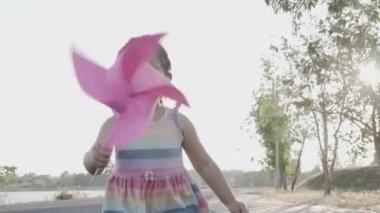 Mutluluk küçük bir kız buğday tarlasında gülümsüyor elinde küçük bir rüzgar tekerleği ya da elinde yel değirmeni oyuncağı