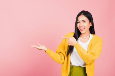 Asyalı güzel bir kadın gülümsüyor pembe arka planda parmakla işaret ediyor, Taylandlı mutlu kadın yüzü boş bir yere bakıyor metin için fotokopi alanından uzaklaşmaya çalışıyor.