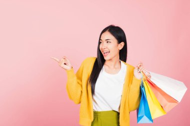 Asyalı mutlu genç kadın alışverişçinin portresi. Heyecanlı gülümsüyor. Elinde online alışveriş poşetleri var.