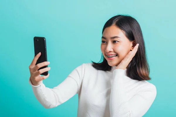 美しいアジアの女性の笑顔彼女は青の背景に隔離された携帯電話にスマートフォンで写真を自撮り 携帯電話で幸せな女性の写真を使用して 技術の概念 — ストック写真