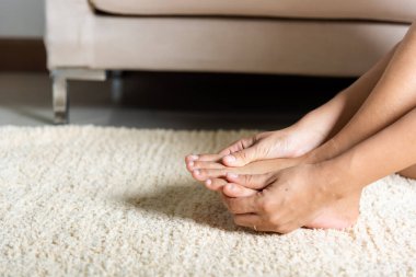 Ayak ağrısı, Asyalı bir kadın ayak parmağını tutuyor, ayak ağrısı çekiyor, ayak ağrısı çekiyor, kadın ayak masajı yapıyor, el masajı yapıyor, evde ayak parmaklarını rahatlatıyor, sağlık sorunları yaşıyor, sağlık sorunları yaşıyor.