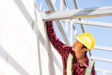 İnşaat işçisi ya da müteahhit ev iskeletini kontrol ediyor, inşaat alanında çelik çatı inşaatçısı çalışıyor.