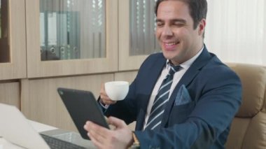 Mutlu iş adamı tabletinde haber okuyor gülümsüyor, iş adamı masasında tek başına çalışıyor elinde dijital tablet tutuyordu.