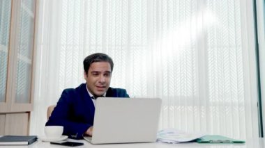 Mutlu iş adamı, beyaz ofis masasında bilgisayarını açıp kağıt hesap dökümanları fırlatan patron kağıtları fırlatıyor ve başarılı oluyor.