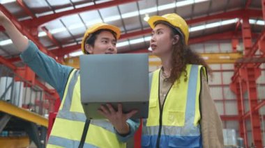 Çalışan iki Asyalı işçi ve kadın takım güvenlik üniforması giyer. Metal levha fabrikası atölyesinde dizüstü bilgisayarla sıkı bir toplantı yaparlar. Mühendislik konuşur ve dizüstü bilgisayarda veri gösterirler.