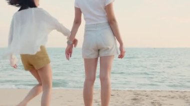 Mutlu arkadaşlar el ele tutuşup hayatın tadını çıkarıyorlar kumsalda birlikte özgürlüğün tadını çıkarıyorlar gün batımında tatil tatilinde genç Asyalı kadın ve erkek yaz seyahatinde, insanların yaşam tarzı