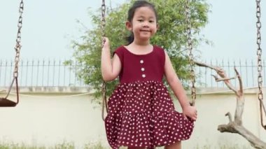 Mutlu gülümseyen küçük kız dışarıda oyun oynarken salıncakta sallanırken eğlen, özgürlük çocuğu yazın günbatımında zincir sallarken.