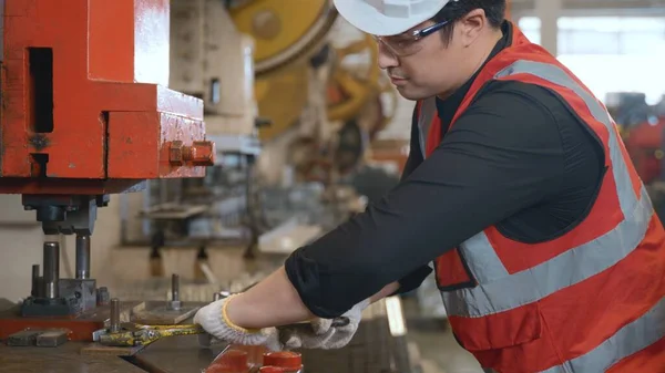 Worker man machine tightening nut, mechanic is repairing the machine with an adjustable wrench at metal sheet factory, industry manufacturing maintenance