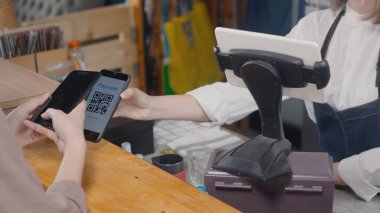 QR kod ödemesi, dijital akıllı telefon uygulaması kullanan müşteri kadın kafeteryada kahve almak için para olmadan QR kod ödemelerini tarıyor, küçük işletme dijital ödeme kabul ediyor