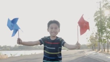 Mutluluk küçük çocuk buğday tarlasında gülümsüyor küçük rüzgar çarkı ya da yel değirmeni oyuncağı tutuyor