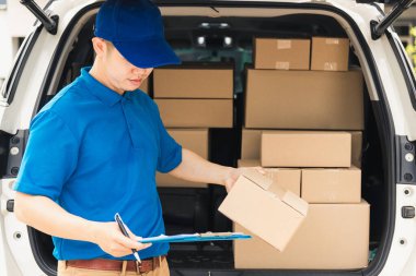 Üniformalı Asyalı genç kurye evrakları pano kontrol listesi posta kutularını müşteriye servis sevkiyatı için bir arabanın yanında tutuyor, çevrimiçi alışveriş hizmeti kavramları