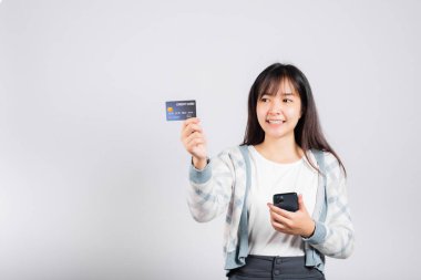 Gülümseyen bir kadın cep telefonu ve kredi kartı ile ödeme stüdyosu için kredi kartı, izole edilmiş beyaz arka plan, akıllı telefon alan ve online alışveriş yapan mutlu genç kadın.