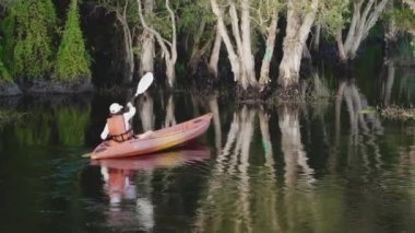 Yazın bir gölde kano süren genç bir kadın. Kırsal alanda, macera seyahati, eğlence konsepti, yaşam tarzı spor tatili.