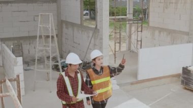 Mimar ve istemci, inşaat alanındaki binanın planıyla planı tartışıyor