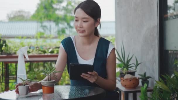 亚洲美丽的年轻女子微笑着拿着技术牌匾到菜园外的盆栽质量 喜爱家庭植物 生活方式 小商业理念等清单上查看 — 图库视频影像