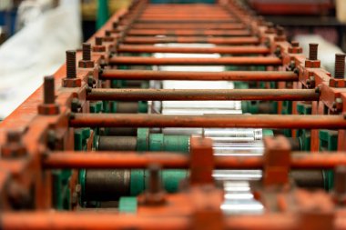 Fabrikada metal borular ve borular üretmek için çelik çatı oluşturma makinesi. Metal kaplama tavan bobinleri için endüstriyel makine.