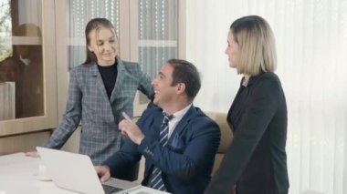 Bir grup genç iş adamı ofiste bir dizüstü bilgisayarla birlikte çalışıyorlar proje ekibi patronla konuşuyor bilgisayarla iş planını tartışmak için mutlu çalışma günleri.