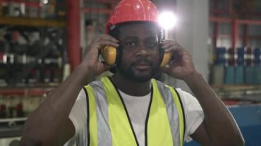 Başarılı fabrika işçisi, fabrika bakım portresi üniformalı siyah mühendislik kaskını çıkar ve kollarını göğsüne kavuşturup kameraya bak.