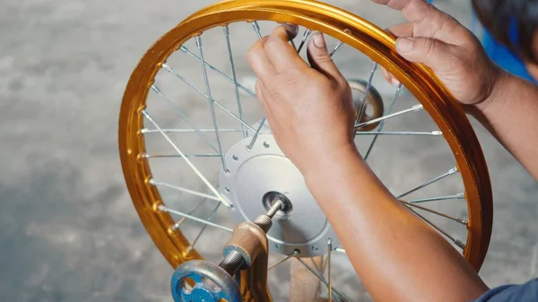 Technician man working motorcycle wheel has spokes weave up on mechanic new steel wheel, Motorcycle spokes wheel alignment machine tool