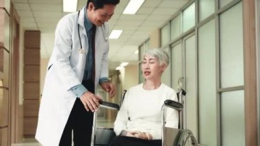 Doktor hastane koridorunda ameliyattan önce tekerlekli sandalyedeki yaşlı bir kadınla konuşuyor.