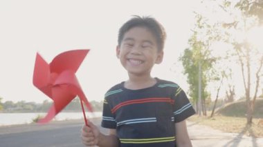 Mutluluk küçük çocuk buğday tarlasında gülümsüyor küçük rüzgar çarkı ya da yel değirmeni oyuncağı tutuyor