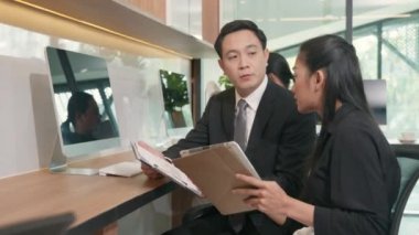 İki iş adamı birlikte sonuçları gösteren çizelge ve grafikleri tartışıyorlar. Asya iş dünyası iş ortaklığı konuşmaları ve masa başındaki başarılarının bütçe analizi grafiği.