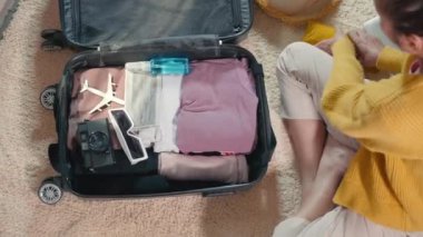 Woman packing clothes, face mask protection, laptop computer and camera in luggage, Preparation travel suitcase packing for new journey at home, Travel vacation traveling after quarantine coronavirus