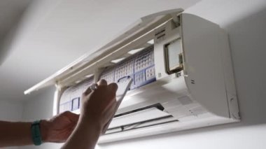 Klimayı kontrol eden profesyonel bir teknisyen yatak odasındaki havalandırma ve onarım için havalandırmaya bakıyor.